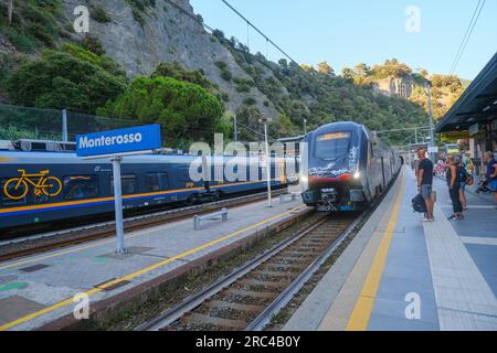 2023 giugno Monterosso, Italia: Treno regionale che arriva alla stazione di Monterosso attraverso il paesaggio montano e passeggeri. Foto Stock