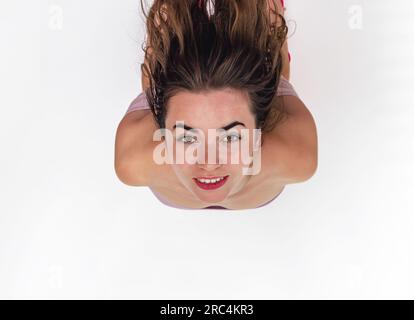 Sorridente faccia di donna. La testa viene rigettata. Capelli scuri, sopracciglia nere, occhi marroni. Vista dall'alto Foto Stock