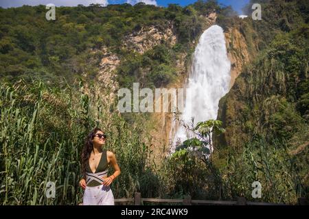 Allegra giovane turista in abiti estivi vicino alla potente cascata di El Chiflon e alla scogliera nel Chiapas, Messico Foto Stock