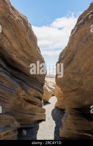 Da sotto, incredibile vista della sezione del pendio montano formata da strati di lava solidificati durante l'eruzione vulcanica contro il cielo blu nuvoloso alla luce del giorno Foto Stock