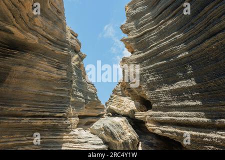 Da sotto, incredibile vista della sezione del pendio montano formata da strati di lava solidificati durante l'eruzione vulcanica contro il cielo blu alla luce del giorno Foto Stock