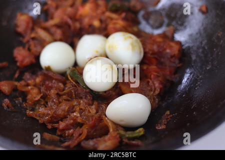 Uova di quaglia arrosto in stile kerala servito in teglia di ghisa. Si ottiene mescolando l'uovo sodo con il masala di pomodoro con cipolla rossa, piccante e caramellata Foto Stock