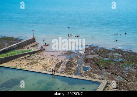 Lo scalo e la piscina di marea sulla scogliera ovest di Ramsgate in un giorno d'estate. Persone che si godono il mare su piccole barche, canoe e tavole da paddle. Foto Stock