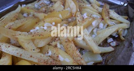 Primo piano delle patate al forno con cipolla ed erbe in un piatto da forno Foto Stock