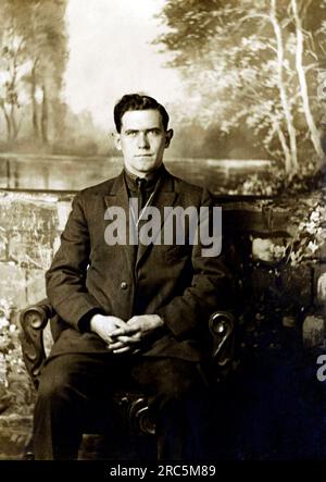 Un uomo che ha il suo ritratto scattato mentre sedeva in un ambiente di studo con uno sfondo, circa 1914. Foto Stock