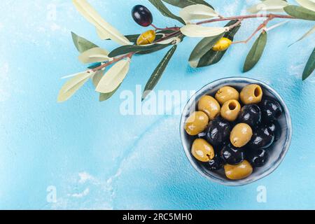 Olive greche nere e verdi in una ciotola su sfondo blu e soleggiato. Copia spazio Foto Stock