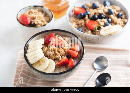 Cereali d'avena per colazione con banana e fragole in ciotola imbevuti di latte di mandorla, pasto per colazione vegano sano Foto Stock