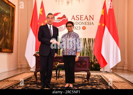 Giacarta, Indonesia. 12 luglio 2023. Il direttore dell'Ufficio della Commissione centrale per gli affari esteri Wang Yi (L) stringe la mano al ministro degli Esteri indonesiano Retno Marsudi durante la riunione a Giacarta, in Indonesia, il 12 luglio 2023. Crediti: Xu Qin/Xinhua/Alamy Live News Foto Stock