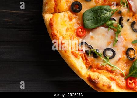Pizza italiana con jerky, formaggio, olive ed erbe su uno sfondo di legno scuro, vista dall'alto. Foto Stock