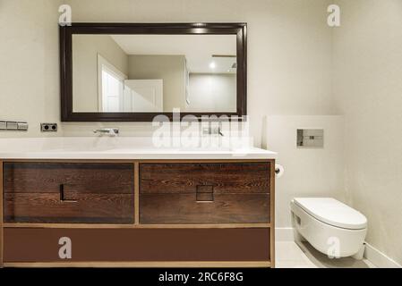 Bagno con grande armadietto in legno scuro con cassetti e specchio con grande cornice in legno Foto Stock