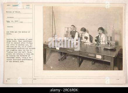 I lavoratori del Bureau of Mines sono visti testare la durezza dei contenitori di cartucce utilizzando una versione modificata del test di Brinell. Questo test è essenziale per garantire che le cartucce possano essere estratte dopo il lancio, evitando così malfunzionamenti temporanei delle armi. I lavoratori contribuiscono agli sforzi bellici aiutando a identificare rapidamente potenziali problemi e a mantenere l'efficienza delle armi da fuoco. Fotografia scattata il 14 maggio 1918. Foto Stock