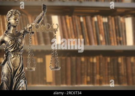 Legge e saggezza. Statua di Lady Justice vicino a scaffali con libri, spazio per il testo Foto Stock