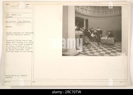 CPL. Combs è visibile in questa fotografia, scattata il 19 marzo 1919, presso l'Adjutant General's Office. L'immagine mostra la filiale 0-R del personale (stanza 450), dove sono state collocate le unità di archiviazione a causa dello spazio insufficiente nelle sale di archiviazione. È possibile vedere un carro da consegna che fa i suoi giri sullo sfondo. Questa immagine è stata pubblicata e approvata dal M.I.D. Censor il 22 marzo 1919. Foto Stock