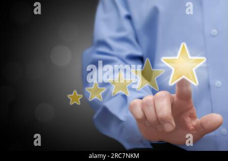 L'uomo tocca con il dito l'icona della valutazione a cinque stelle (votazione). Concetto di feedback dei clienti e dei consumatori. Foto Stock