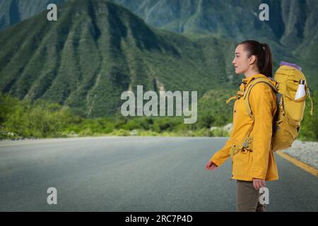 Turista con zaino su strada vicino alle montagne Foto Stock