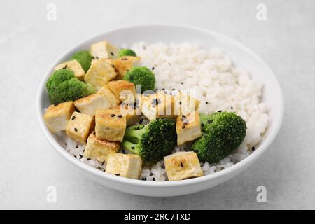 Ciotola di riso con tofu fritto e broccoli su tavolo bianco, primo piano Foto Stock