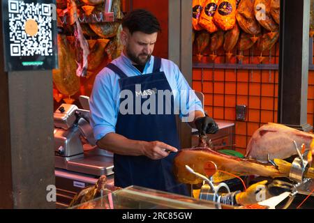 Uomini che tagliano una gamba di prosciutto stagionato Foto Stock