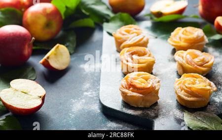 Mini crostate con rose di mele e zucchero a velo sul tagliere di pietra. Foto Stock