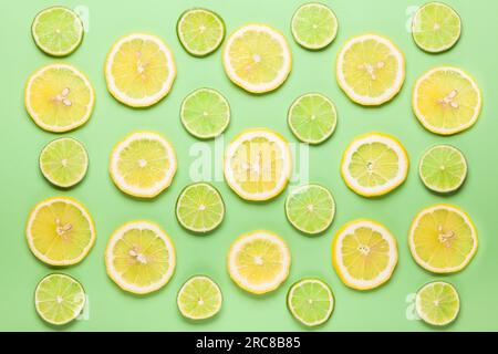 Fette di limone fresco e motivo lime su sfondo verde pastello in stile minimalista. Base piatta, spazio copia. Foto Stock
