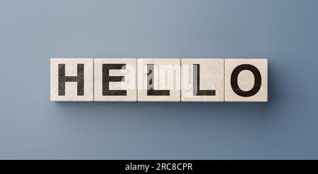 Saluto o saluto per dare il benvenuto a qualcuno o avviare una conversazione. Disegna con lettere su cubi di legno su sfondo blu. Comunicazione c Foto Stock
