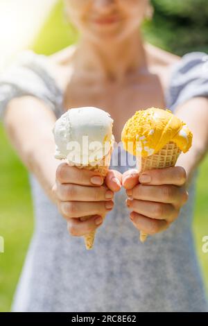 Le mani delle donne tengono un gelato rinfrescante in coni di waffle con un pizzico di saporito sapore di limone Foto Stock