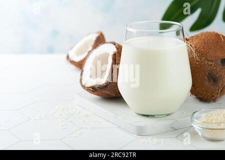 Bicchiere di latte di cocco e primo piano su uno sfondo bianco con spazio per il testo. Latte di cocco vegano non caseario o latte senza latticini. In salute Foto Stock