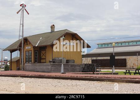 Bertram, Texas - 8 giugno 2023: Storico deposito ferroviario con biblioteca sullo sfondo il giorno delle nuvole a Bertram, Texas Foto Stock