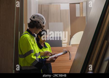 team del personale che lavora nella fabbrica dell'industria del mobile in legno che controlla l'inventario del compensato materiale di stagionatura del bordo di legno in magazzino. Foto Stock