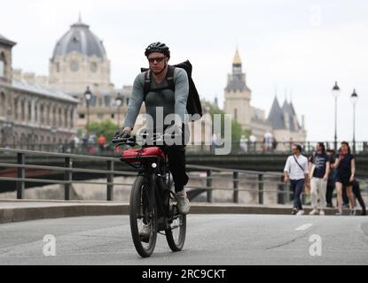 (230713) -- PARIGI, 13 luglio 2023 (Xinhua) -- Un motociclista passa per la Senna a Parigi, Francia, 28 giugno 2023. La Senna, il secondo fiume più grande della Francia, si snoda attraverso il cuore di Parigi. Scorrendo da ovest a est, divide la città nelle iconiche "Right Bank" e "Left Bank". La riva sinistra è caratterizzata da un'atmosfera artistica, adornata da caffè, teatri e librerie, che creano un paradiso per il circolo letterario e un paradiso culturale. D'altra parte, la riva destra ospita prestigiosi monumenti storici come il Louvre, l'ex palazzo reale e l'Elysee Palace, l'attuale Foto Stock