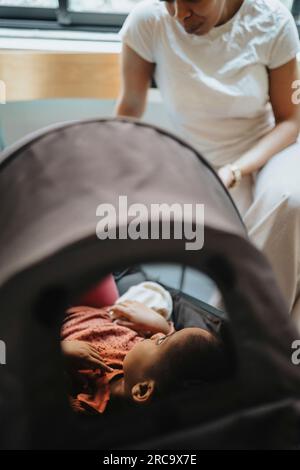 Madre che parla con una figlia malata che giace nel passeggino in sala d'attesa Foto Stock