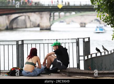 (230713) -- PARIGI, 13 luglio 2023 (Xinhua) -- una coppia si riposa sulla Senna a Parigi, Francia, 28 giugno 2023. La Senna, il secondo fiume più grande della Francia, si snoda attraverso il cuore di Parigi. Scorrendo da ovest a est, divide la città nelle iconiche "Right Bank" e "Left Bank". La riva sinistra è caratterizzata da un'atmosfera artistica, adornata da caffè, teatri e librerie, che creano un paradiso per il circolo letterario e un paradiso culturale. D'altra parte, la riva destra ospita prestigiosi monumenti storici come il Louvre, l'ex palazzo reale e il Palazzo Elysee, il Foto Stock