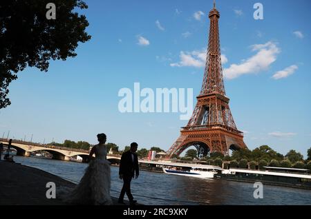 (230713) -- PARIGI, 13 luglio 2023 (Xinhua) -- una coppia dalla Cina posa per le foto di matrimonio del fiume Senna a Parigi, Francia, 27 giugno 2023. La Senna, il secondo fiume più grande della Francia, si snoda attraverso il cuore di Parigi. Scorrendo da ovest a est, divide la città nelle iconiche "Right Bank" e "Left Bank". La riva sinistra è caratterizzata da un'atmosfera artistica, adornata da caffè, teatri e librerie, che creano un paradiso per il circolo letterario e un paradiso culturale. D'altra parte, la riva destra ospita prestigiosi monumenti storici come il Louvre, l'ex palazzo reale, e. Foto Stock