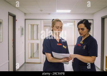 Personale medico di sesso femminile che esamina i documenti mentre si trova al centro sanitario Foto Stock