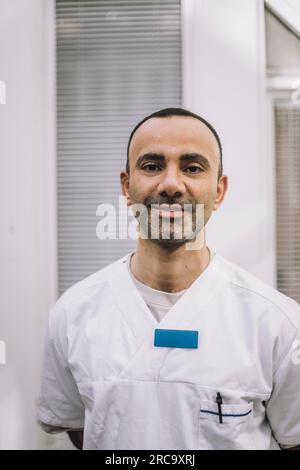 Ritratto di un medico maschio maturo sorridente che indossa il cappotto da laboratorio all'ospedale Foto Stock