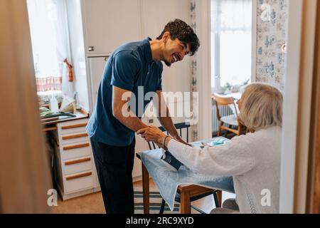 Uomo felice che assiste la donna anziana a casa Foto Stock