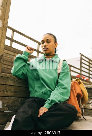 Ritratto di una giovane donna con uno zaino seduto sui gradini Foto Stock