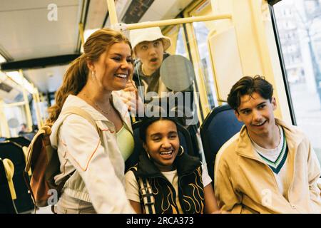 Felici amici maschi e femmine che si divertono mentre viaggiano in treno Foto Stock