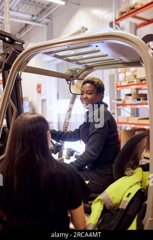 Un'operatore sorridente che parla con un collega in un magazzino di distribuzione Foto Stock