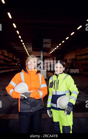 Ritratto di donne sorridenti che lavorano in abiti riflettenti nell'industria del legname Foto Stock