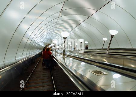 scala mobile per metropolitana, interni in metallo, lampade. le persone salgono sulla scala mobile. San Pietroburgo, Russia - 5.7.22 Foto Stock