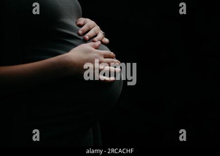 donna incinta che tiene la pancia del bambino Foto Stock