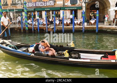 Una giovane coppia che si gode il giro in gondola sul Canal grande con uno striscione contro la mafia di Venezia in un palazzo sul lungomare di Riva del Vin, Italia Foto Stock