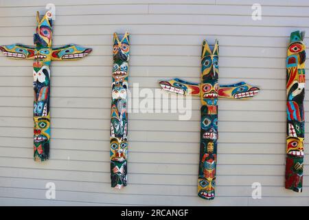 Pali totem dipinti in legno nativi appesi su un muro all'esterno del Ye Olde Curiosity Shop Pier 54 Seattle Washington State USA Foto Stock