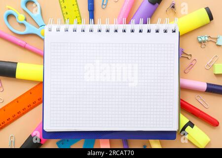 Cornice realizzata in cancelleria diversa con notebook vuoto su sfondo beige Foto Stock