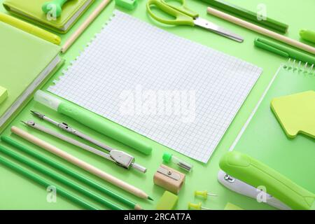 Notebook vuoto con cancelleria diversa su sfondo verde Foto Stock