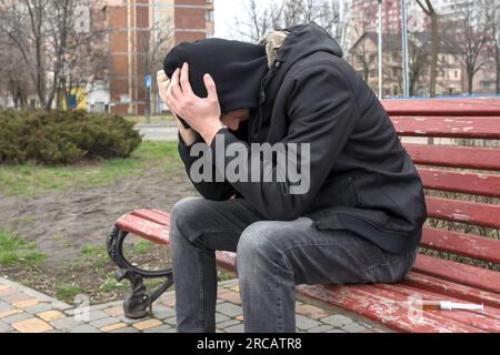 Un tossicodipendente per strada in crisi dopo aver assunto droghe. Concetto di dipendenza. Foto Stock