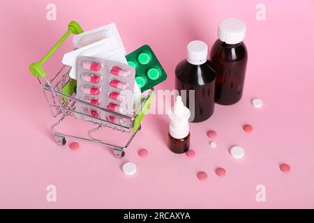 Mini carrello con diversi farmaci su sfondo rosa Foto Stock