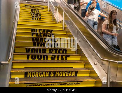 Le scale della Penn Station a New York portano un avviso pubblicitario che avverte le persone di guardare il loro passo, dallo studio legale Morgan & Morgan, visto martedì 4 luglio 2023. (© Richard B. Levine) Foto Stock