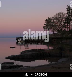 Scena del tramonto a vita Sannar, Svezia. Alberi e panchina sulla riva del lago Vanern Foto Stock