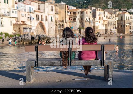 Due donne che si godono la vista del centro storico di Cefalù durante una serata di sole in Sicilia. La storica Cefalù è una delle principali mete turistiche della Sicilia. Foto Stock